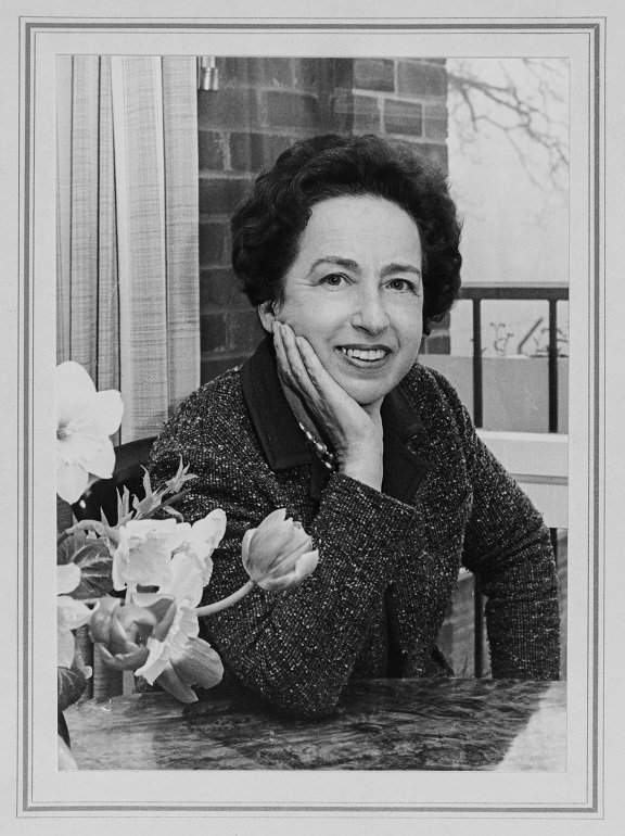 Dr. Viola Klein posing with her elbow on a table near a vase of flowers
