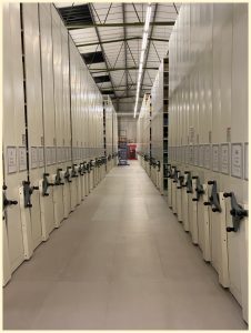 An image showing numerous rows of roller racking disappearing into the distance. A blue ladder at the far end is dwarfed by the height of the racks.